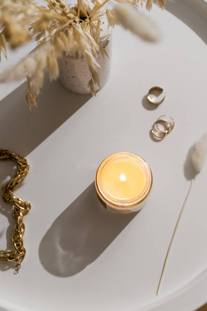istock White burning candle on coffee table with gold jewelry accessories, home decorations 2189013585