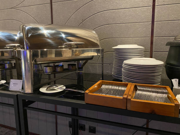 istock Buffet table setting in hotel or restaurant. Chafing dish, stack of white plates, soup cup, forks, spoon and soup kettle 2189015263