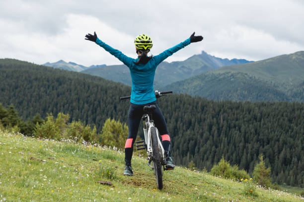 istock Cheering woman cyclist on beautiful forest mountain top 2189015924