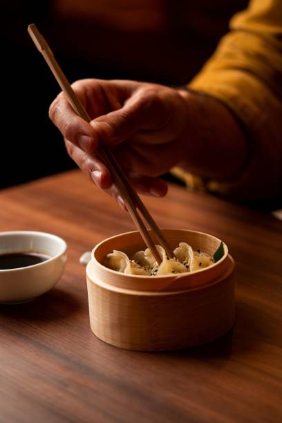 istock Hand picking dumplings with chopsticks from bamboo steamer. 2189016004