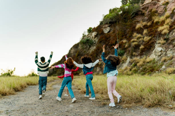A multiracial group of Generation Z friends relaxing together in a large field, enjoying each others company on a day off.  They lay in the grass, eyes closed.