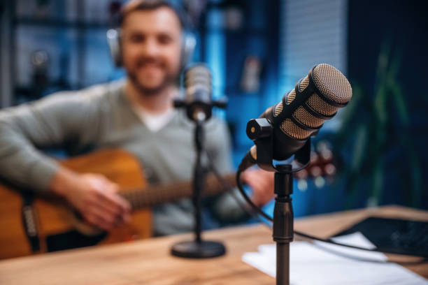 istock In headphones, playing guitar. Man with microphone in the studio, conception of podcast 2189019044