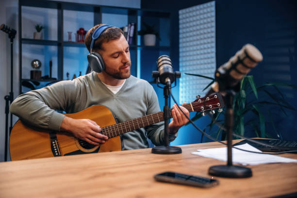 istock In headphones, playing guitar. Man with microphone in the studio, conception of podcast 2189019057