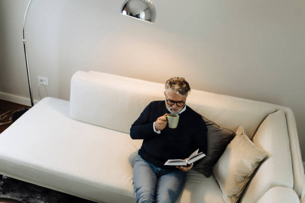 istock Senior man reading book and resting at home 2189020936