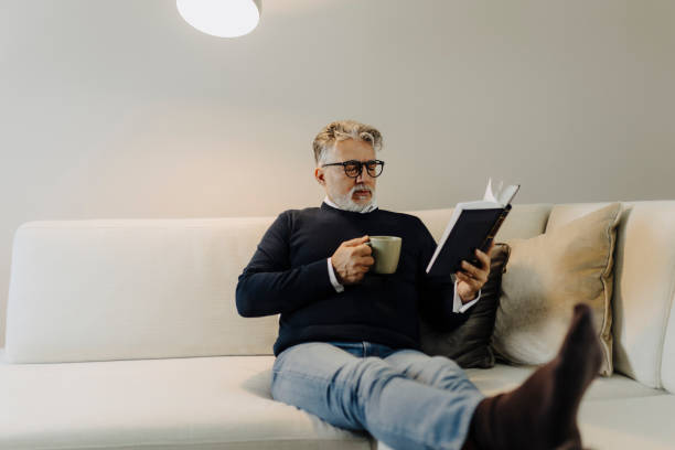 istock Senior man reading book and resting at home 2189021248