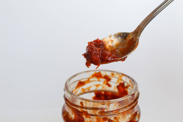 istock Sambal is an Indonesian chilli sauce or paste. On a silver spoon, taken from a transparent glass jar. Isolated on white background 2189021530