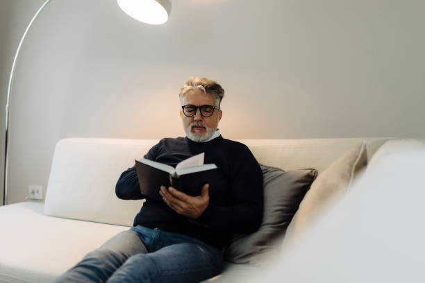 istock Senior man reading book and resting at home 2189021910