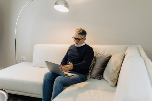 istock Mature adult man using laptop at home 2189022422