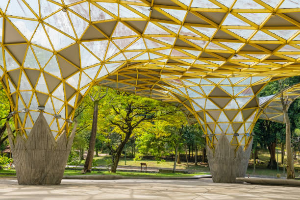 istock Perdana Botanical Garden, Kuala Lumpur, Malaysia with modern architectural structure with a yellow geometric roof and large open space surrounded by greenery and trees under a bright blue sky 2189025850