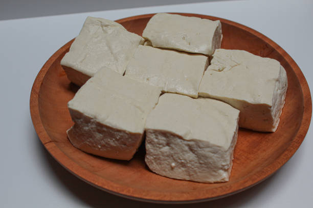istock Uncooked white tofu on a wooden plate, isolated on white background 2189025956