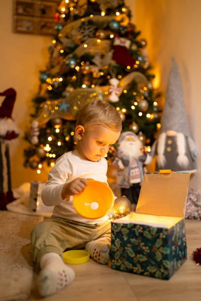 istock Child Opening Christmas Present Under Decorated Christmas Tree at Home 2189027136