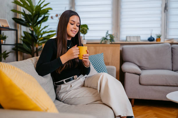 istock Young Woman Drinking Coffee While Sitting On The Sofa At Home 2189028012