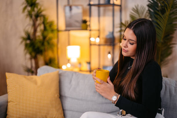 istock Young Woman Drinking Coffee While Sitting On The Sofa At Home 2189028030