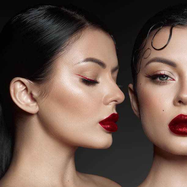 istock Two models showcase stunning makeup with bold red lips and intricate eyeliner designs. dark background enhances their flawless skin and elegant poses, emphasizing the artistry involved 2189032297