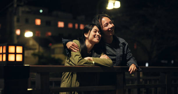 istock Bridge, couple and happy at night with hug for bonding, sightseeing and explore for fun in Japan. People, relationship and smile outdoor on evening date for fresh air, support and care as lovers 2189035247