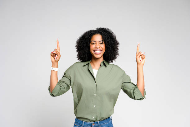 istock African-American woman with a beaming smile points upwards with both index fingers 2189036348