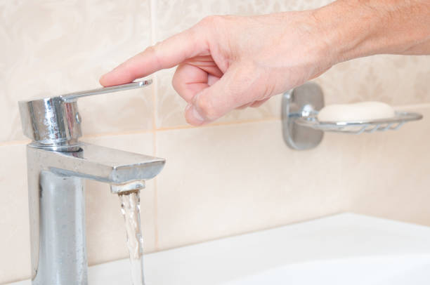 istock Man's hand turns off the water in the tap 2189037384