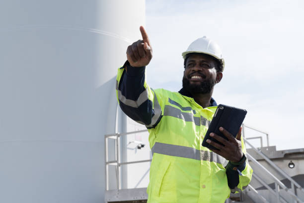 istock African American male engineer using digital tablet checking system of wind turbine at windmill field farm station. Male engineer monitoring and control windmill system at wind turbines station 2189038613