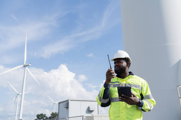 istock African American male engineer using digital tablet checking system of wind turbine at windmill field farm station. Male engineer monitoring and control windmill system at wind turbines station 2189038624