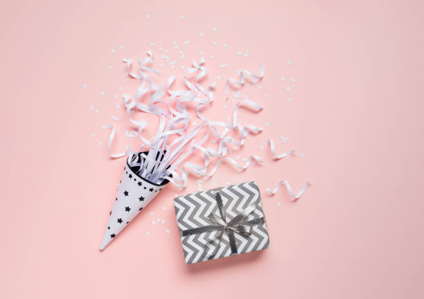 Cheerful festive background scene featuring a cute gift with ribbon and confetti celebratory streamers.For occasions like birthdays, holidays and celebrations,this vibrant and elegant setup captures the joy of giving.