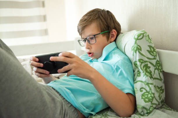 istock Teenager boy with mobile phone laying on bed, watching at screen. Digital technology, gadget addiction. Social media communication, playing game, web surfing 2189041946