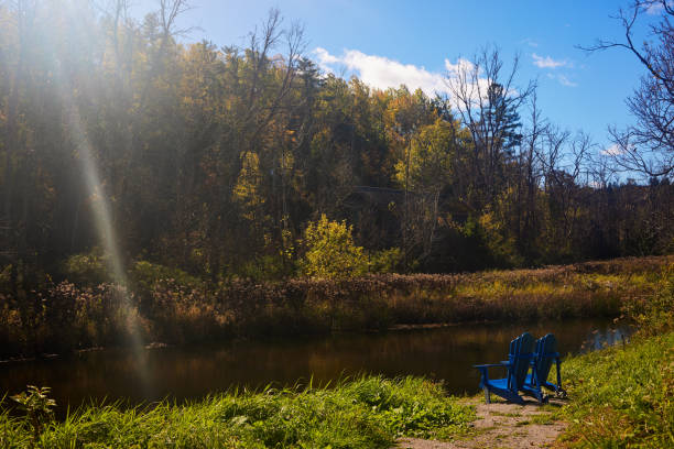 istock Serene Autumn Landscape With Adirondack Chairs By A Tranquil River 2189042162