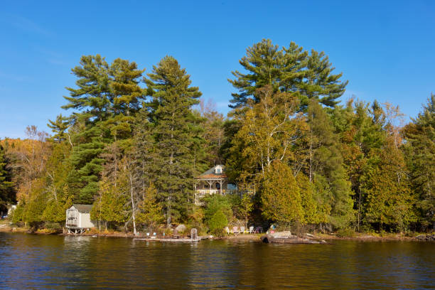 istock Cozy Lakeside Cabin Surrounded By Tall Green Trees And Clear Blue Sky 2189042372