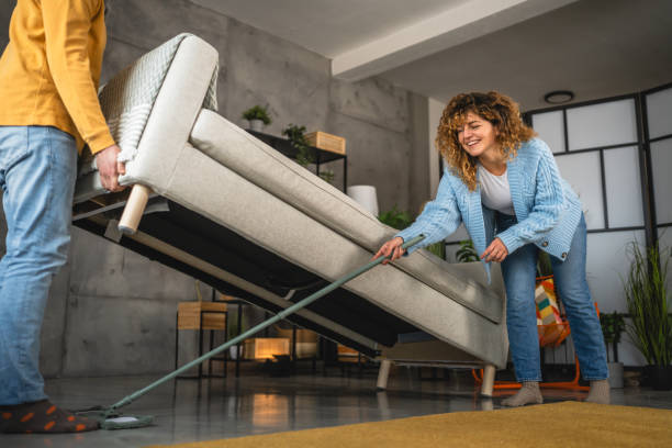 istock couple do chores clean floor with a broom under the raised sofa 2189042581