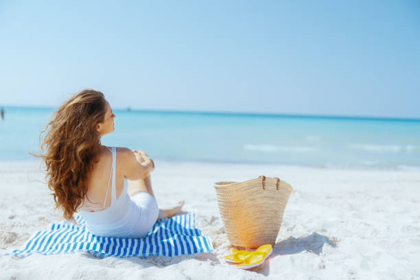 istock Seen from behind modern female on ocean coast with straw bag 2189044247