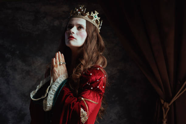 istock medieval queen in red dress with crown praying 2189045606
