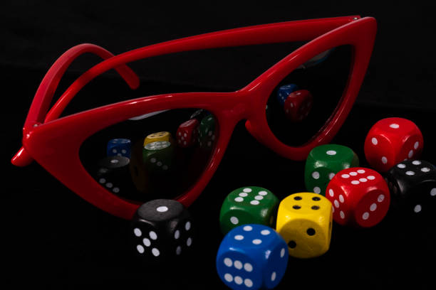 Red cat eye sunglasses and dice cubes on black background nearby. High quality photo