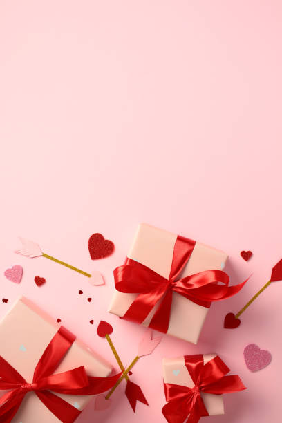 istock Valentine's Day vertical banner with pink gift boxes wrapped in red ribbons, surrounded by glittery hearts and decorative arrows on a pink background. Perfect for romantic and festive occasions 2189049073