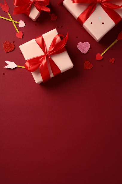 istock February 14 Valentine Day vertical background with gift boxes, surrounded by heart-shaped decorations and Cupid's arrows on a red background. Flat lay, top view. 2189049355