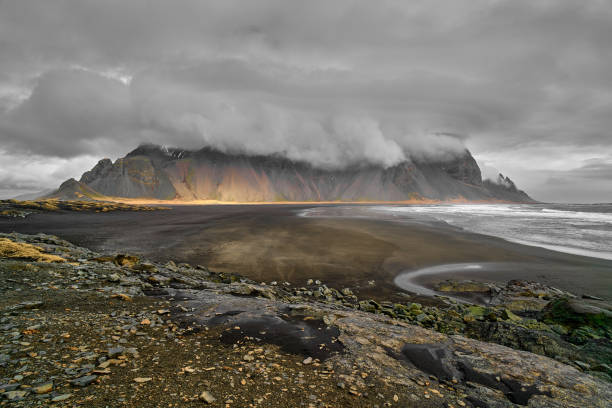 istock Dramatic sky covering mountain range with black sand beach in foreground 2189052970
