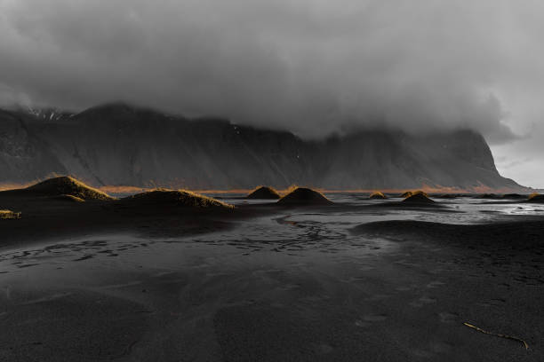 istock Black sand beach with golden light touching grass on small hills 2189053061