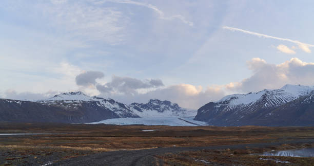 istock Dirt road leading to snowy mountains and glacier under cloudy sky 2189053848