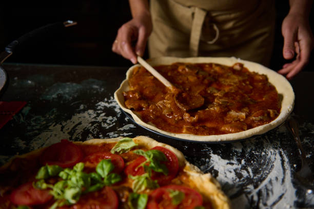 istock Chef preparing homemade pizza with tomato sauce and fresh ingredients 2189059671