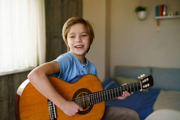 istock Happy boy playing a guitar at home 2189061497