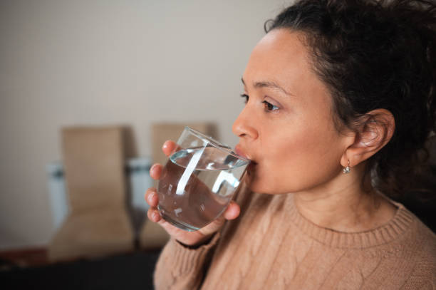 istock Woman drinking clear water from a glass in a calm indoor setting 2189062020