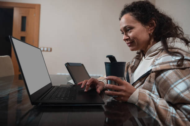 istock Woman working on laptop while holding a coffee mug at home 2189062925