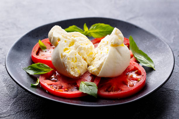 istock Caprese salad with tomatoes, burrata cheese and basil. Grey background. Close up. 2189062946
