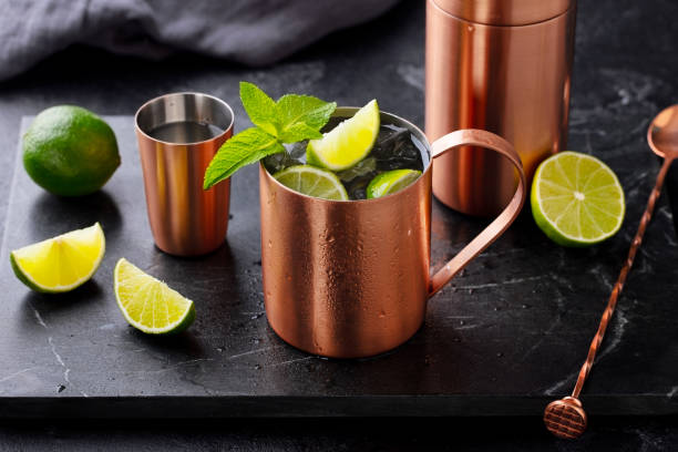 istock Moscow mule cocktail in copper mug, shaker with fresh mint, lime on marble board. Dark background. Close up. 2189063458