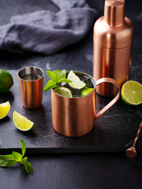 istock Moscow mule cocktail in copper mug, shaker with fresh mint, lime on marble board. Dark background. Close up. 2189063520