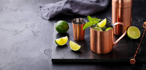 istock Moscow mule cocktail in copper mug, shaker with fresh mint, lime on marble board. Dark background. Copy space. 2189063588