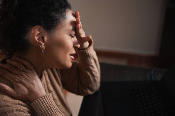 istock Stressed woman holding neck while working on a laptop at home 2189063649