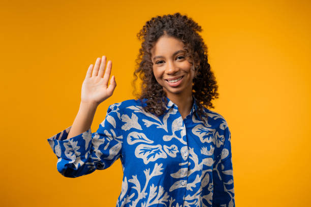 istock Friendly african eoman waving hand - Hello, Hi, Salute. Greetings on yellow 2189064097