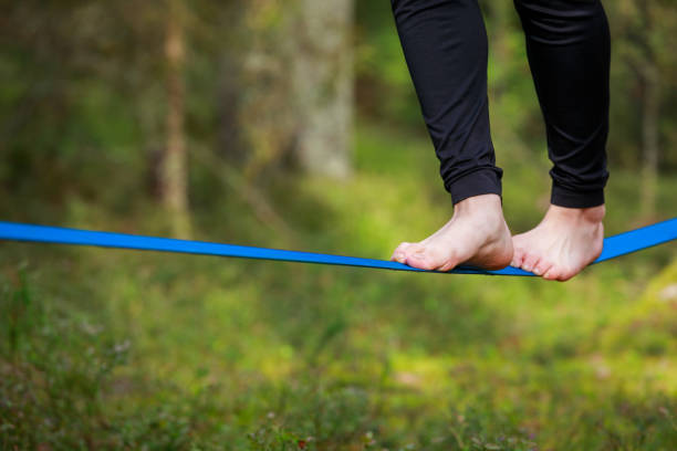 istock Close-up of feet balancing on a slackline in a lush forest setting 2189064295