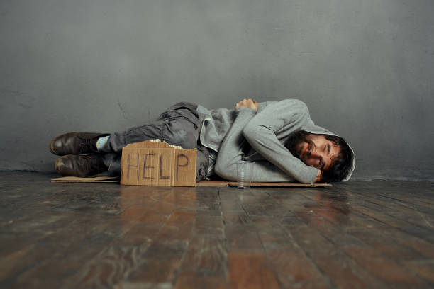 A homeless man lies in the middle of the street.
