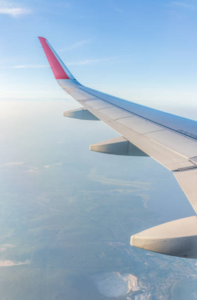 View from the airplane window at a beautiful cloudy sky and the airplane wing. Earth and sky as seen through window of an airplane.