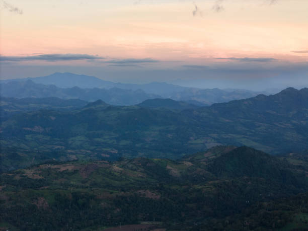 Many green hills landscape background in orange sunset light aerial view